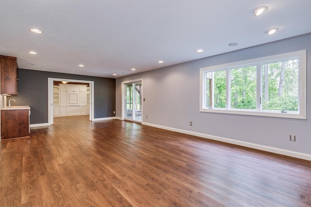 1469 Sherman Lake Rd, Lino Lakes, MN 55038 - unfurnished living room with dark wood-type flooring, recessed lighting, baseboards, and a sink