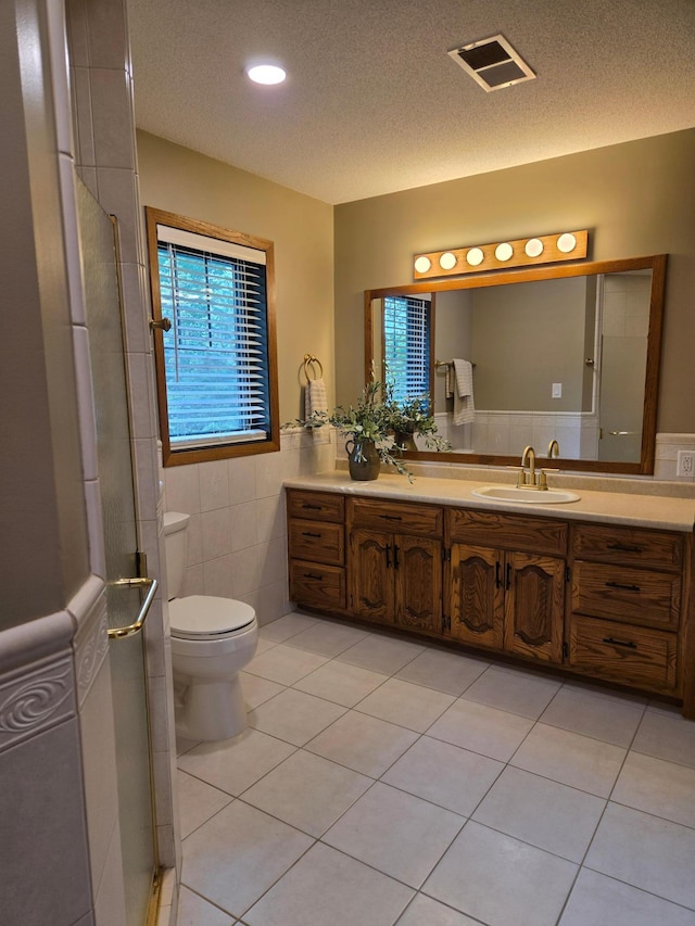 1410 16th St SW, Willmar, MN 56201 - bathroom with tile walls, vanity, tile patterned flooring, toilet, and a textured ceiling