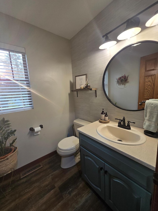 1410 16th St SW, Willmar, MN 56201 - bathroom featuring toilet, vanity, wood finished floors, and baseboards