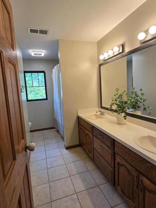 1410 16th St SW, Willmar, MN 56201 - full bathroom featuring tile patterned flooring, double vanity, toilet, and baseboards