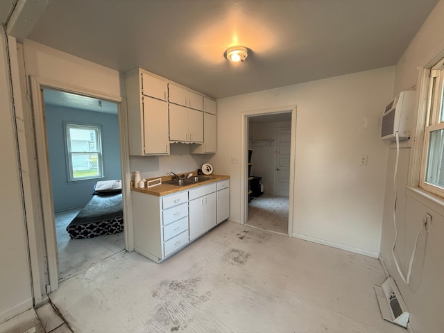139 Petrick St, Appleton, MN 56208 - kitchen featuring a sink, white cabinetry, a wall mounted air conditioner, and baseboards