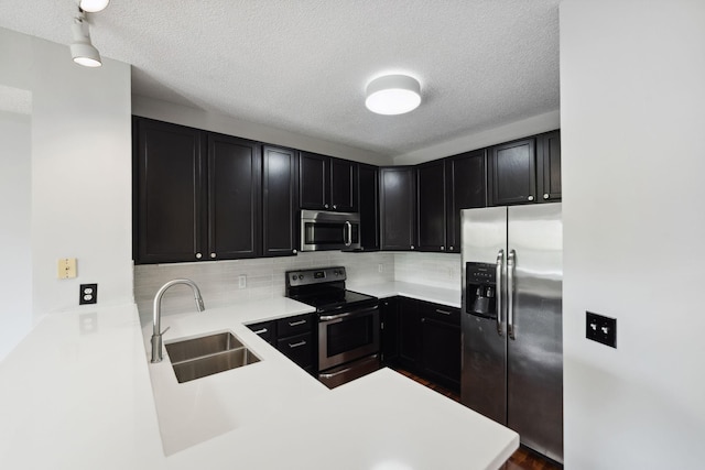 615 1st St Unit 405, Minneapolis, MN 55401 - kitchen featuring appliances with stainless steel finishes, a sink, dark cabinetry, backsplash, and a textured ceiling