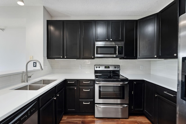615 1st St Unit 405, Minneapolis, MN 55401 - kitchen with appliances with stainless steel finishes, a sink, dark cabinets, dark wood-style flooring, and a textured ceiling