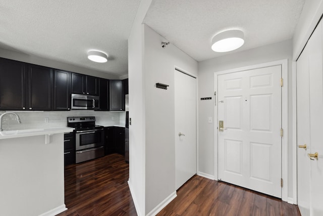 615 1st St Unit 405, Minneapolis, MN 55401 - kitchen featuring stainless steel appliances, dark cabinetry, dark wood-style flooring, light countertops, and backsplash
