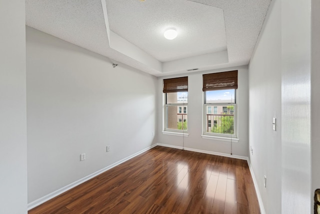 615 1st St Unit 405, Minneapolis, MN 55401 - spare room with a textured ceiling, dark wood-style flooring, baseboards, and a raised ceiling