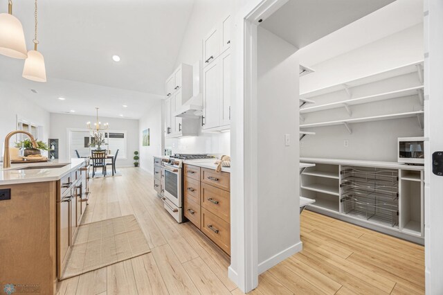 4295 Bristlecone Loop S, Fargo, ND 58104 - kitchen featuring a sink, white gas stove, light wood finished floors, a chandelier, and pendant lighting