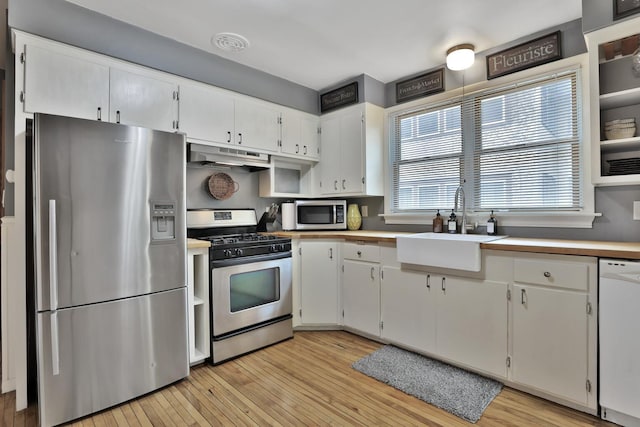 1807 Minnehaha Ave W, Saint Paul, MN 55104 - kitchen featuring appliances with stainless steel finishes, under cabinet range hood, a sink, light wood-style floors, and white cabinetry