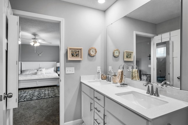 7243 Ada Dr, Lino Lakes, MN 55038 - ensuite bathroom with double vanity, a textured ceiling, a ceiling fan, and baseboards