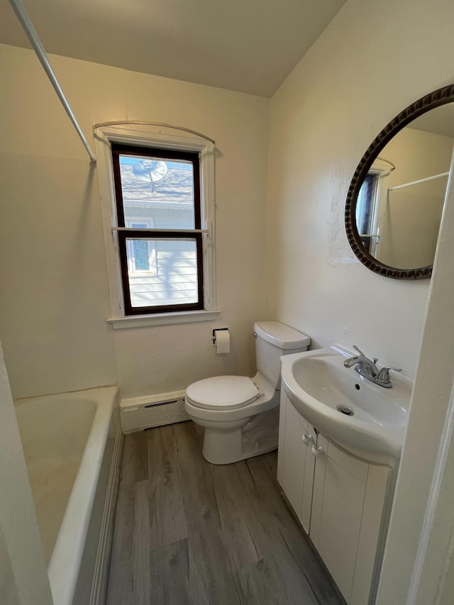 2619 2nd Ave W, Hibbing, MN 55746 - bathroom featuring baseboard heating, vanity, wood finished floors, toilet, and washtub / shower combination