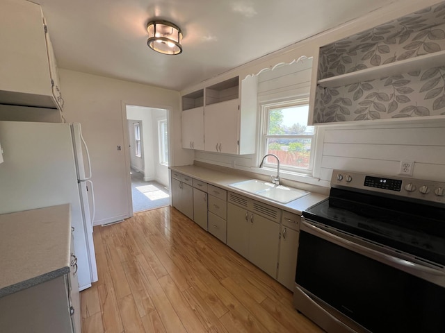 2619 2nd Ave W, Hibbing, MN 55746 - kitchen featuring stainless steel range with electric cooktop, a sink, open shelves, freestanding refrigerator, and light wood-style floors