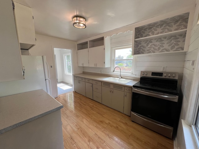 2619 2nd Ave W, Hibbing, MN 55746 - kitchen with stainless steel electric stove, light wood-style flooring, open shelves, light countertops, and freestanding refrigerator