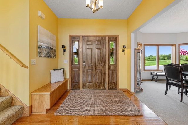 1900 Legacy Dr, Faribault, MN 55021 - foyer featuring light wood-type flooring, stairway, a chandelier, baseboards, and a textured ceiling