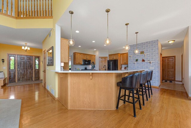 1900 Legacy Dr, Faribault, MN 55021 - kitchen featuring black appliances, light wood-style flooring, open shelves, a peninsula, and a breakfast bar