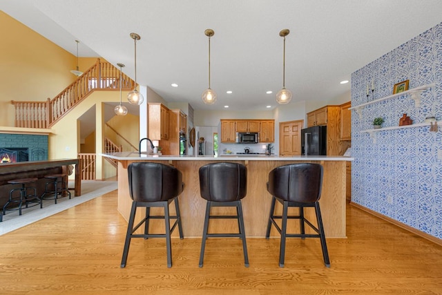 1900 Legacy Dr, Faribault, MN 55021 - kitchen featuring stainless steel microwave, wallpapered walls, light wood finished floors, light countertops, and a peninsula