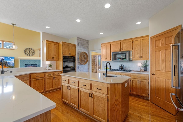 1900 Legacy Dr, Faribault, MN 55021 - kitchen with stainless steel microwave, a sink, light countertops, a center island with sink, and a textured ceiling