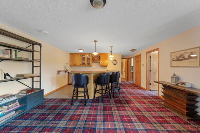 1900 Legacy Dr, Faribault, MN 55021 - kitchen with carpet floors, a breakfast bar, hanging light fixtures, a textured ceiling, and glass insert cabinets