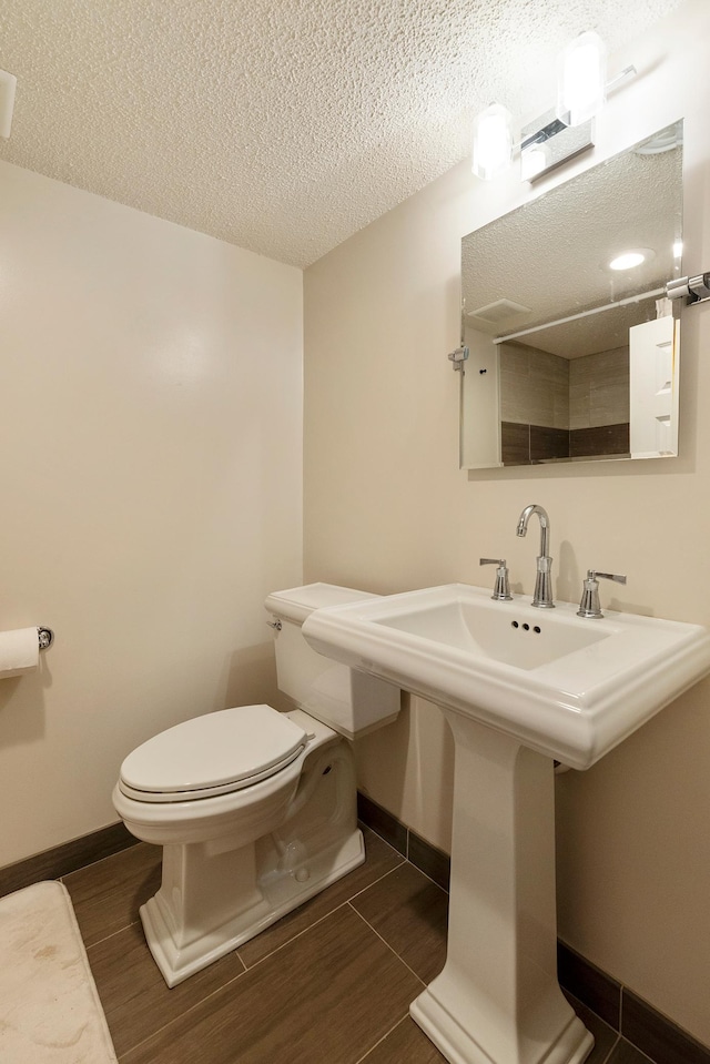 18799 147th St NW, Elk River, MN 55330 - half bath featuring a textured ceiling, baseboards, toilet, wood finished floors, and a sink
