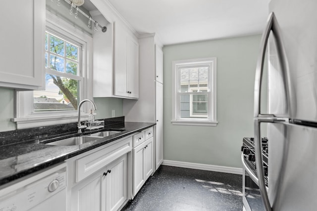5737 Vincent Ave S, Minneapolis, MN 55410 - kitchen featuring appliances with stainless steel finishes, baseboards, a sink, white cabinetry, and dark stone counters