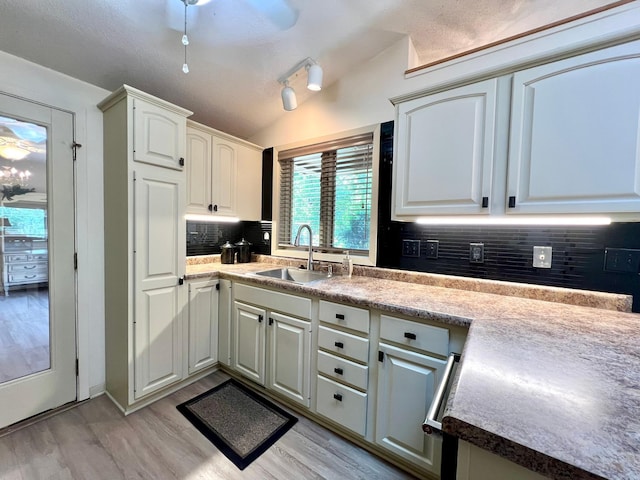 1319 3rd St, Red Wing, MN 55066 - kitchen featuring a sink, light wood-style flooring, backsplash, white cabinetry, and lofted ceiling