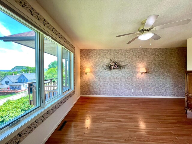 1319 3rd St, Red Wing, MN 55066 - unfurnished room with wallpapered walls, baseboards, wood finished floors, a textured ceiling, and ceiling fan
