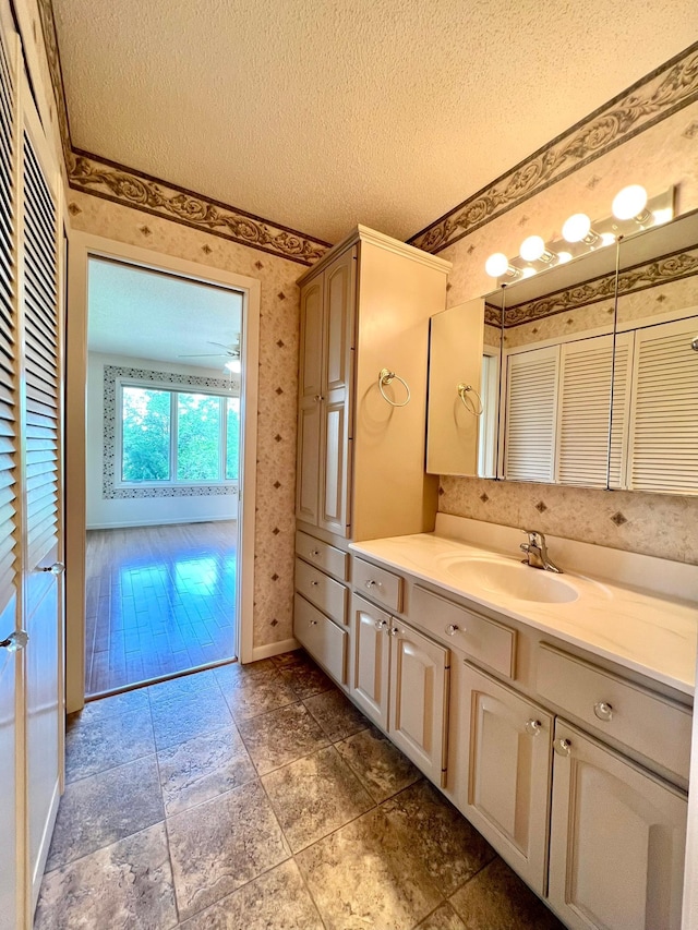 1319 3rd St, Red Wing, MN 55066 - bathroom with wallpapered walls, a textured ceiling, vanity, baseboards, and a closet