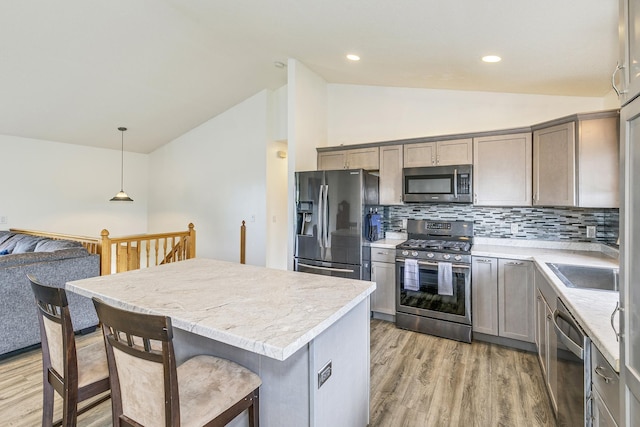 918 Mallard St NE, Hanover, MN 55341 - kitchen with appliances with stainless steel finishes, vaulted ceiling, light wood finished floors, tasteful backsplash, and a kitchen island