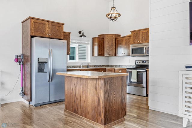 934 31st Ave W, West Fargo, ND 58078 - kitchen featuring appliances with stainless steel finishes, a high ceiling, light wood-style flooring, a kitchen island, and a chandelier