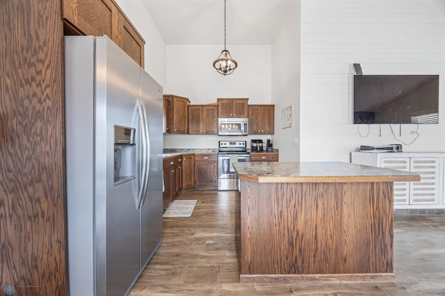 934 31st Ave W, West Fargo, ND 58078 - kitchen with appliances with stainless steel finishes, a kitchen island, a high ceiling, a chandelier, and dark wood-type flooring
