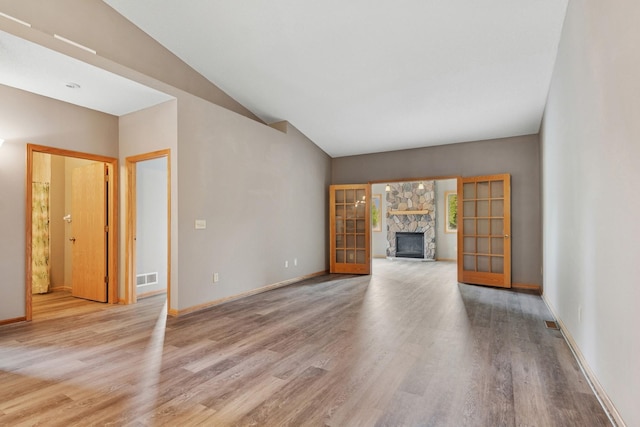 185 21st Ave SW, Cambridge, MN 55008 - unfurnished living room with wood finished floors, a stone fireplace, vaulted ceiling, and baseboards