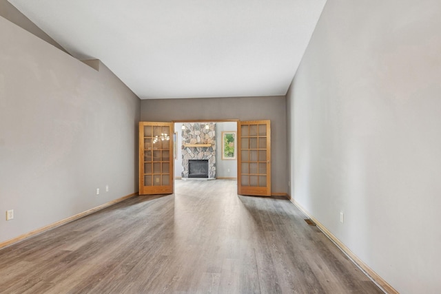 185 21st Ave SW, Cambridge, MN 55008 - unfurnished living room featuring a stone fireplace, wood finished floors, and baseboards