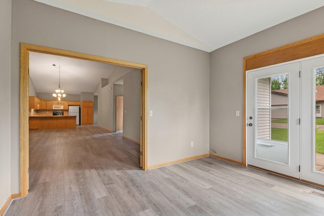 185 21st Ave SW, Cambridge, MN 55008 - unfurnished living room with vaulted ceiling, a chandelier, light wood finished floors, and baseboards
