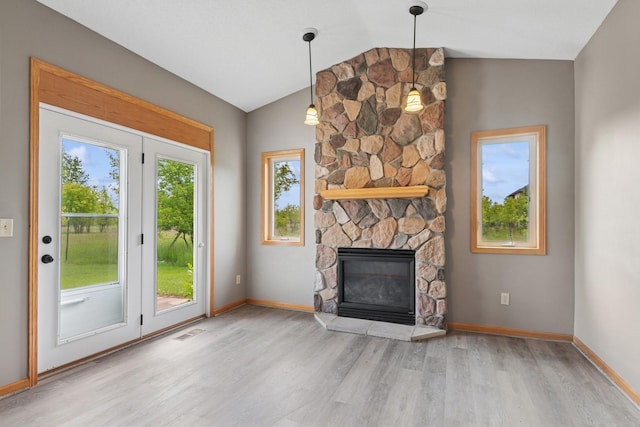 185 21st Ave SW, Cambridge, MN 55008 - unfurnished living room with wood finished floors, vaulted ceiling, baseboards, and a stone fireplace