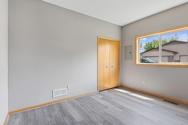 185 21st Ave SW, Cambridge, MN 55008 - unfurnished bedroom with wood finished floors, baseboards, a closet, and electric panel