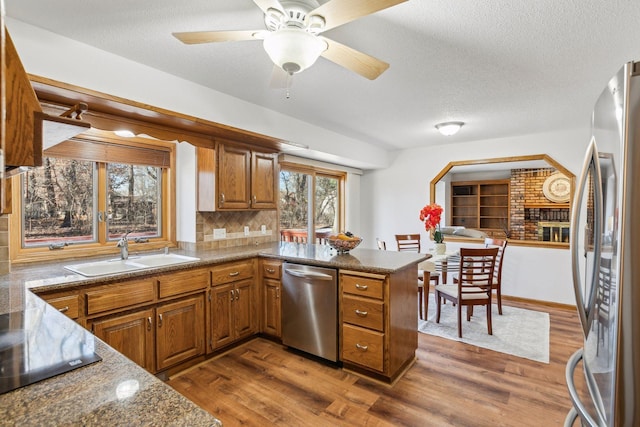 5929 Oxford St N, Shoreview, MN 55126 - kitchen with stainless steel appliances, brown cabinetry, a peninsula, dark wood finished floors, and a textured ceiling
