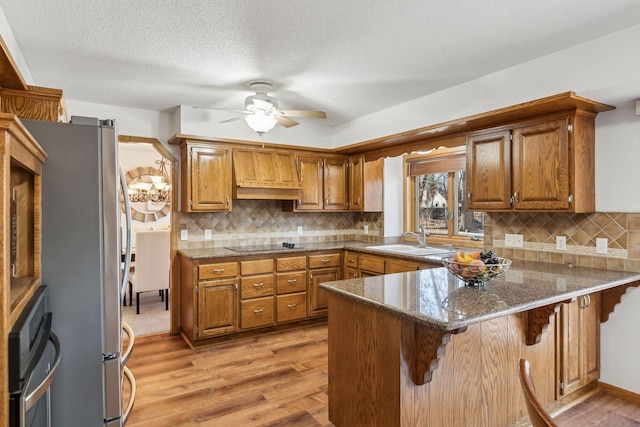 5929 Oxford St N, Shoreview, MN 55126 - kitchen featuring a peninsula, a ceiling fan, brown cabinetry, light wood finished floors, and a textured ceiling