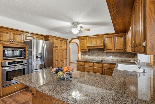 5929 Oxford St N, Shoreview, MN 55126 - kitchen featuring appliances with stainless steel finishes, decorative backsplash, brown cabinets, a peninsula, and a textured ceiling
