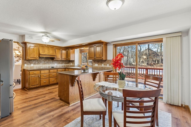 5929 Oxford St N, Shoreview, MN 55126 - kitchen with a peninsula, brown cabinets, a ceiling fan, tasteful backsplash, and a textured ceiling