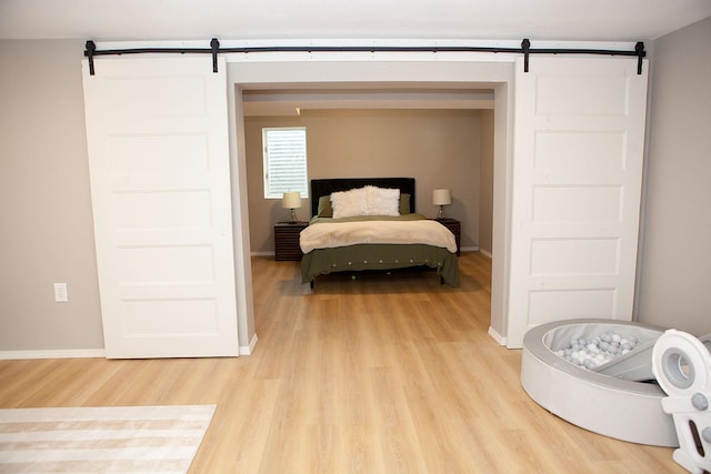 6014 6th St, Lake Park, MN 56554 - bedroom with a barn door, light wood finished floors, and baseboards