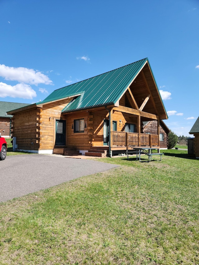 303 Hilltop Ct, Warrens, WI 54666 - log-style house with log siding, a front yard, a metal roof, and a porch