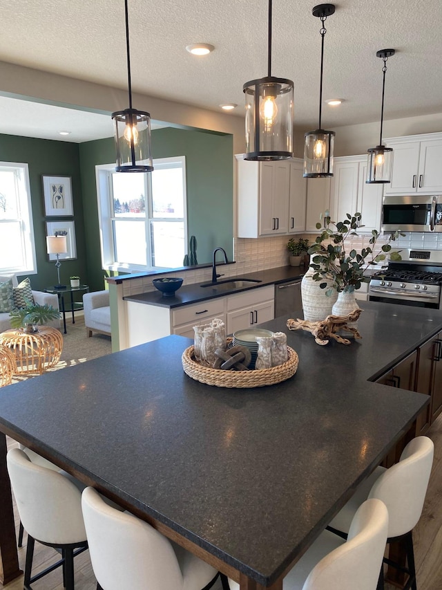 16695 Manor Rd, Eden Prairie, MN 55343 - kitchen with stainless steel appliances, a sink, dark countertops, a spacious island, and a textured ceiling