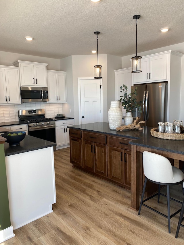 16695 Manor Rd, Eden Prairie, MN 55343 - kitchen featuring stainless steel appliances, dark countertops, light wood-style floors, white cabinets, and recessed lighting