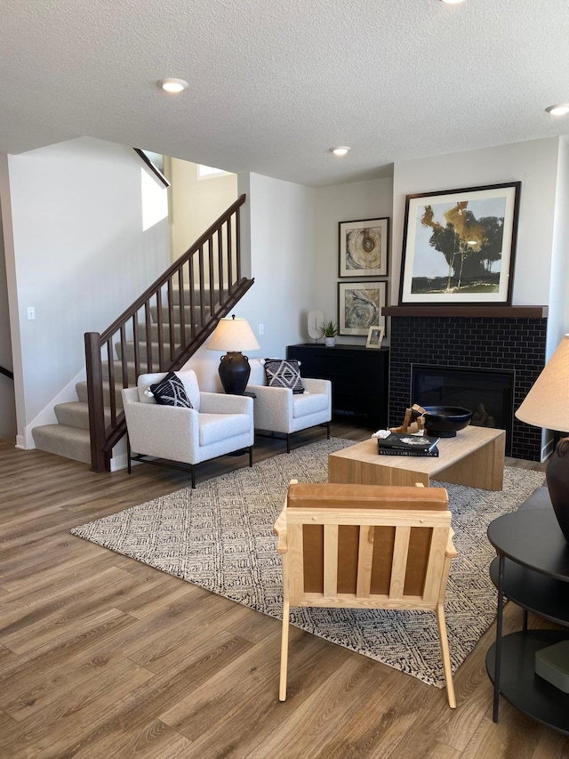 16695 Manor Rd, Eden Prairie, MN 55343 - living room featuring stairway, wood finished floors, a textured ceiling, a tiled fireplace, and recessed lighting