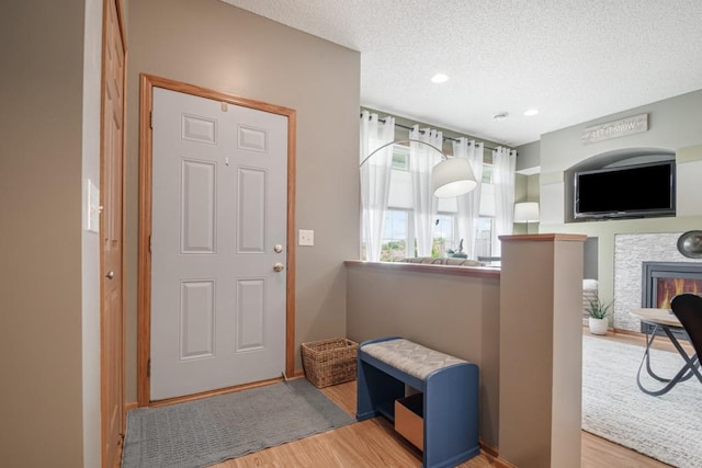 10465 172nd Ln NW, Elk River, MN 55330 - foyer with wood finished floors, a textured ceiling, a stone fireplace, recessed lighting, and baseboards