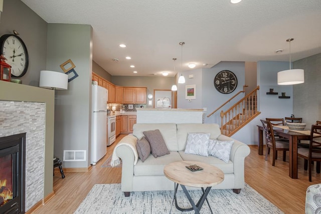 10465 172nd Ln NW, Elk River, MN 55330 - living room featuring stairway, light wood-style floors, a fireplace, recessed lighting, and baseboards
