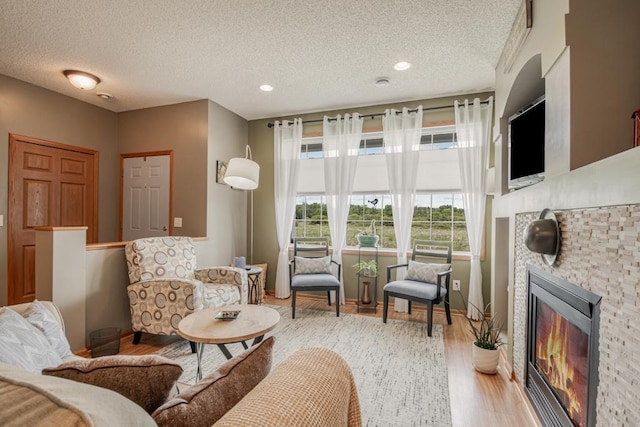 10465 172nd Ln NW, Elk River, MN 55330 - living area featuring a textured ceiling, a glass covered fireplace, light wood finished floors, and baseboards