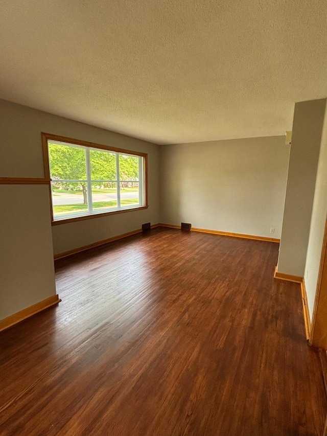 912 Arnold Ave N, Thief River Falls, MN 56701 - empty room featuring dark wood-type flooring, a textured ceiling, and baseboards