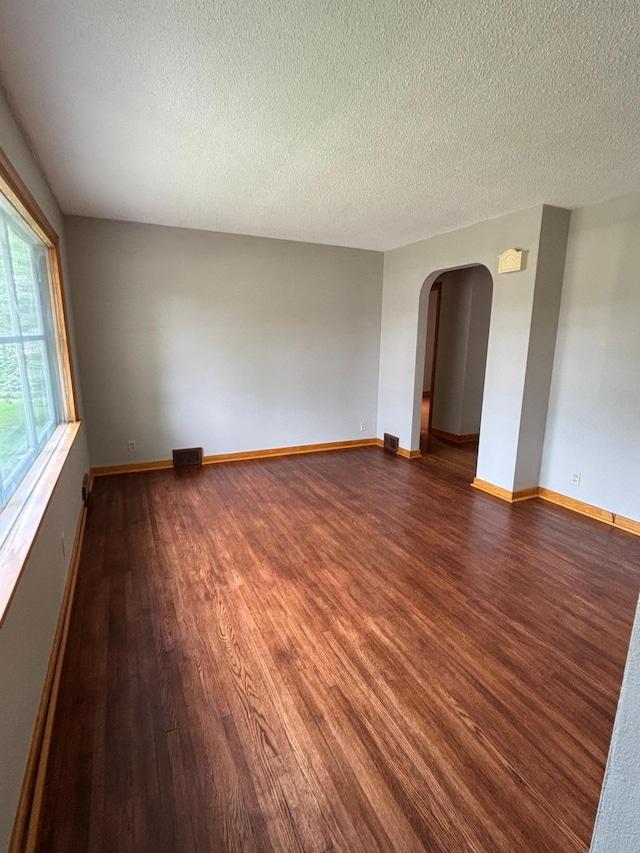 912 Arnold Ave N, Thief River Falls, MN 56701 - unfurnished room featuring wood finished floors, arched walkways, a textured ceiling, and baseboards