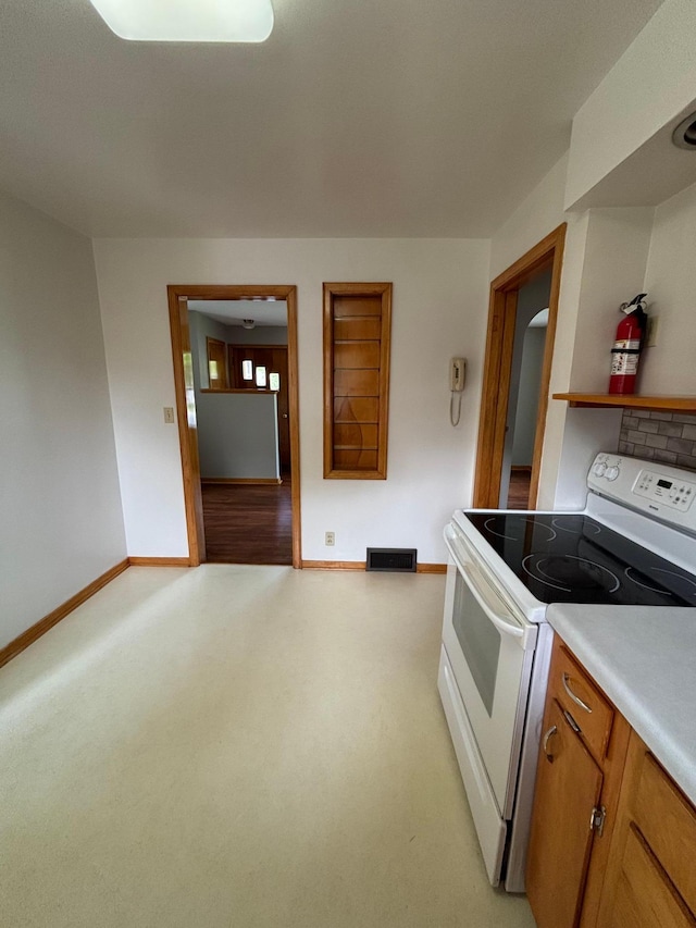 912 Arnold Ave N, Thief River Falls, MN 56701 - kitchen featuring white electric range, baseboards, brown cabinetry, light countertops, and light carpet