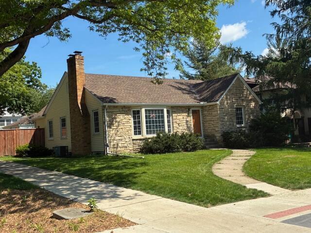 4901 Bryant Ave S, Minneapolis, MN 55419 - view of front of house with stone siding, a chimney, and central AC