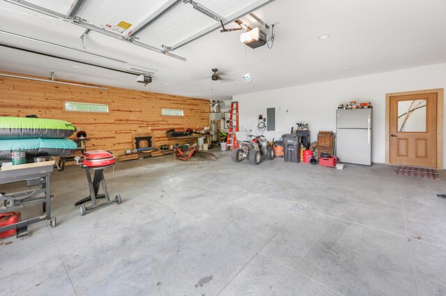 20470 220th St, Verndale, MN 56481 - garage with freestanding refrigerator, electric panel, a garage door opener, wooden walls, and a workshop area